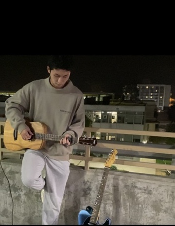 Playing acoustic guitar at night on a rooftop